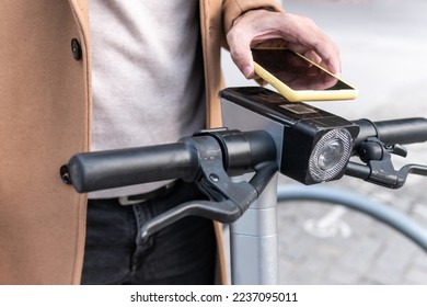 Close-up image of a man's hand contacting his mobile phone to the qr code to rent and unlock an electric scooter. - Powered by Shutterstock