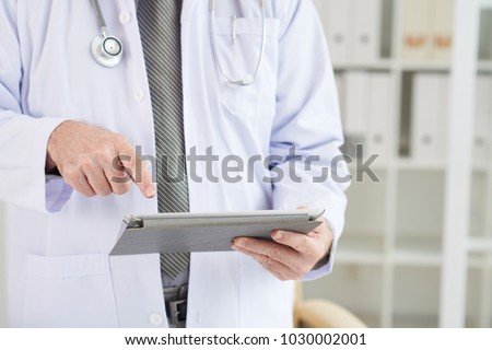 Close-up image of medical worker checking informatio on digital tablet