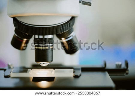 Close-up image of microscope viewing microorganisms on glass slide. Emphasizing detailed view of scientific instrument in laboratory setting