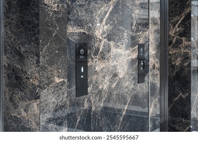 A close-up image of a modern elevator panel with black buttons on a sleek, marble-covered wall. Elevator Panel with Marble Background - Powered by Shutterstock