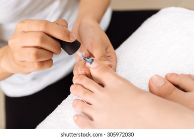 Close-up Image Of Pedicurist Applying Base Coat To The Toenails