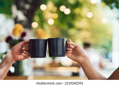 Closeup image of a people clinking coffee cups together in cafe