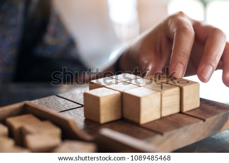 Closeup image of people playing wooden Tic Tac Toe game or OX game 