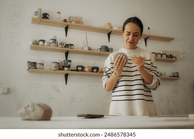 Close-up Image portrait of female ceramic artist working with clay mug and making Ceramic Product. Professional Ceramic Artist makes handcrafted products. Small business and hobby concept - Powered by Shutterstock