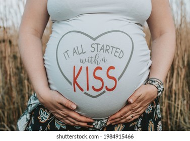 Close-up image of pregnant woman with funny t-shirt  It all started with a kiss written on tshirt over pregnancy belly 