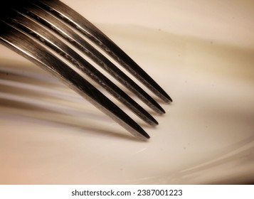 Close-up image of prongs of a fork on a porcelain plate.