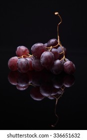 Closeup image of red grapes on black background with reflection