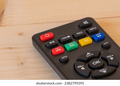 Close-up image of remote control on wooden table.
