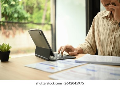 A close-up image of a Remote worker multitasking between a phone call and digital work during business hours.