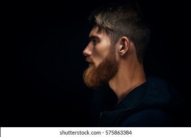 Close-up image of serious brutal bearded man on dark background Confident and dramatic concept - Shutterstock ID 575863384
