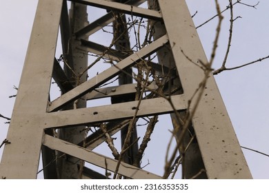 A close-up image of several thin, metal branches forming a complex, geometric shape against a blurred black background