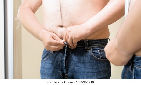 Closeup Image Of Shirtless Fat Man Wearing Tight Jeans At Mirror