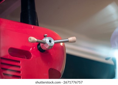 A close-up image showcasing the handle of a red mechanical device. The design highlights the craftsmanship and functional aspects of the equipment.