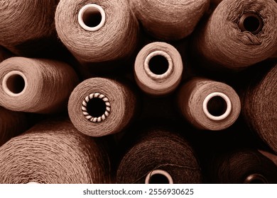 Close-up image showcasing multiple yarn spools in an array of earthy tones. Perfect for concepts related to craft, sewing, and industrial production.Demonstrating color of 2025 year.