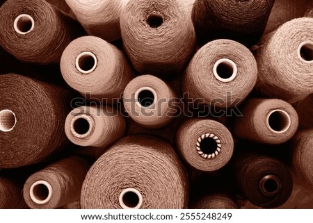 Close-up image showcasing multiple yarn spools in an array of earthy tones. Perfect for concepts related to craft, sewing, and industrial production.Demonstrating color of 2025 year.