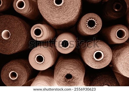 Close-up image showcasing multiple yarn spools in an array of earthy tones. Perfect for concepts related to craft, sewing, and industrial production.Demonstrating color of 2025 year.