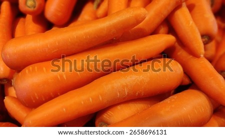 A close-up image showing multiple fresh orange carrots in a natural pile. The vibrant tones and textured skin highlight their organic freshness, ideal for food, agriculture, or diet visuals.