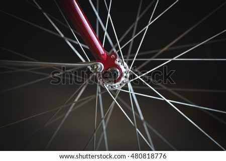 Closeup image shows details of spokes and gears on a red bike.