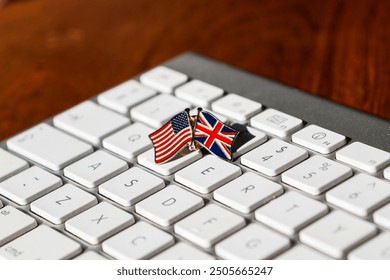 A close-up image of a small pin featuring crossed US and UK flags on a white keyboard, symbolizing international collaboration, digital communication, and the connection between the USA and UK.