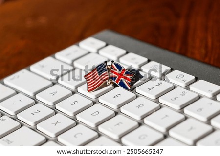 A close-up image of a small pin featuring crossed US and UK flags on a white keyboard, symbolizing international collaboration, digital communication, and the connection between the USA and UK.
