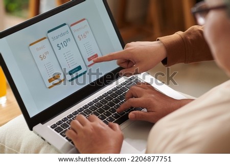Closeup image of son explaining senior mother how to pay for monthly subscription online