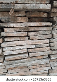 A close-up image of stacked rustic clay bricks, showcasing their rough, weathered texture and eart
