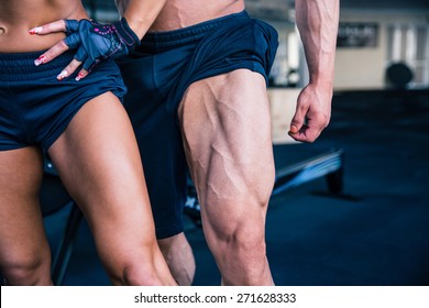 Closeup image of a strong woman and muscular man posing at gym