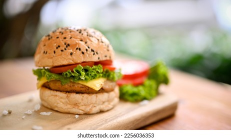 Close-up image of a tasty beef burger with fresh vegetables on wooden tray over blurred background. - Shutterstock ID 2256036353
