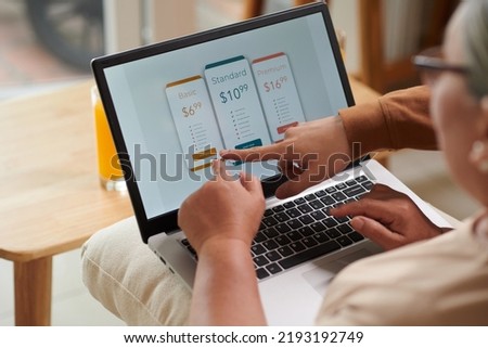 Closeup image of teenage boy explaining grandmother how to pay for online service subscription