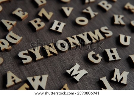 Closeup image of text SYNONYMS surrounded by scattered alphabet. 