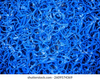 a close-up image of a textured blue plastic mesh, featuring an intricate, tangled arrangement of flexible loops.