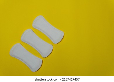 Close-up image of three women's sanitary napkins on a yellow background leaving copy space. Concept of intimate hygiene of the woman when she is with the period.