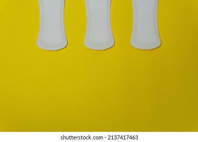 Close-up image of three women's sanitary napkins on a yellow background leaving copy space. Concept of intimate hygiene of the woman when she is with the period.