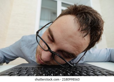 Close-up Image Of Tired Sleepy Businessman Sleeping On His Laptop Against The White Surface. A Tired Programmer In The Office. A Hungover Morning At Work.