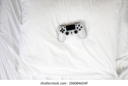 Closeup Image Top View Game Controller, Lying On White Sheets Of Bed At Home With Copy Space