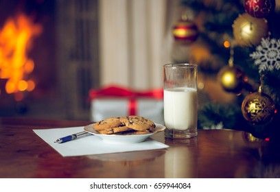 Closeup image of treats and letter to Santa on wooden table next Christmas tree - Powered by Shutterstock