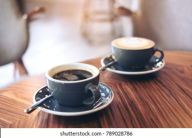 Closeup Image Of Two Blue Cups Of Hot Latte Coffee And Americano Coffee On Vintage Wooden Table In Cafe