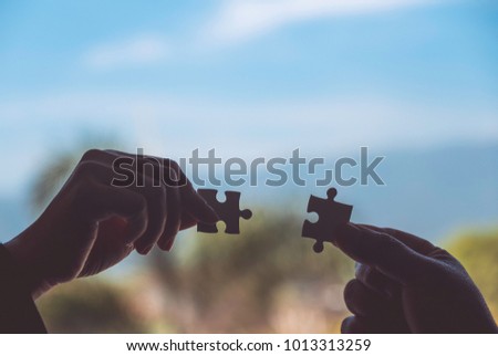 Closeup image of two hands holding a jigsaw puzzle with feeling love 