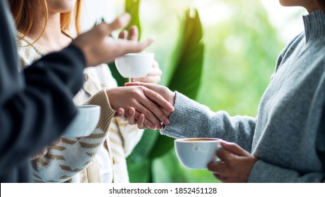 Closeup Image Of Two People Holding Hands While Drinking Coffee Together