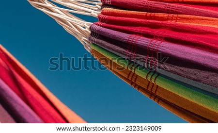 Close-up image of two rainbow colored hammocks against the blue sky