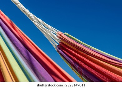 Close-up image of two rainbow-colored hammocks against the blue sky