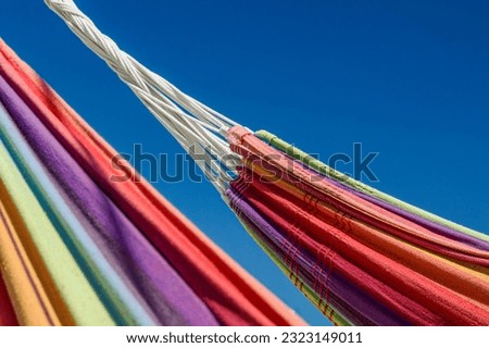 Close-up image of two rainbow-colored hammocks against the blue sky