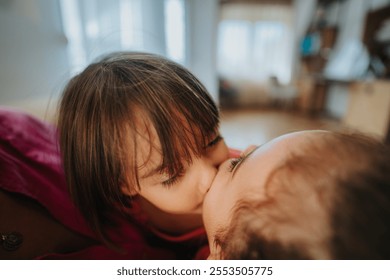 A close-up image of two young siblings affectionately kissing indoors, capturing the warmth and togetherness of family love and bonding moments. - Powered by Shutterstock