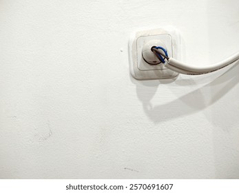 A close-up image of a wall socket with exposed wiring featuring blue and brown cables
