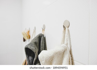 Close-up image of a white bath robe hanging on a hook in a bathroom. Spare minimalistic image of modern bath room details