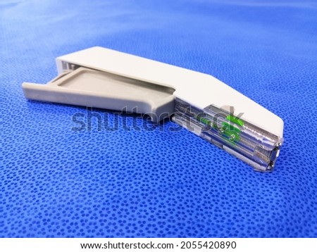 Closeup Image Of White Color Disposable Surgical Skin Stapler In Blue Background. Selective Focus