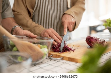 A close-up image of a wife chopping vegetables, cooking, and making a healthy breakfast with her husband in the kitchen. domestic life, home cooking, lifestyle - Powered by Shutterstock