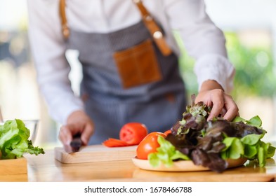 Closeup image of a woman chef prepare lettuce and vegetables to cook in kitchen - Powered by Shutterstock