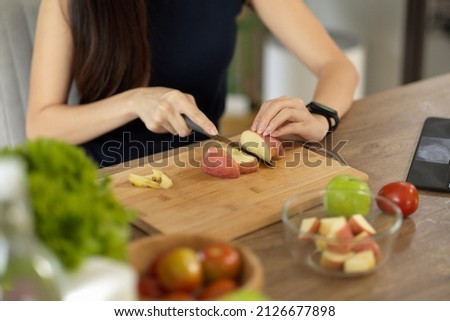 Close-up image, Woman chopping red apples on cutting board, preparing her healthy diet snack. Cooking at home.