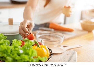 A close-up image of a woman cooking in the kitchen, making a healthy salad, holding a tomato. home cooking, healthy lifestyle, wellness eating, weight loss recipes, domestic life, leisure - Powered by Shutterstock